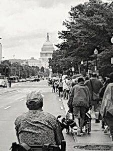 Disability rights activists march toward the U.S. Capitol carrying signs and pushing wheelchairs
